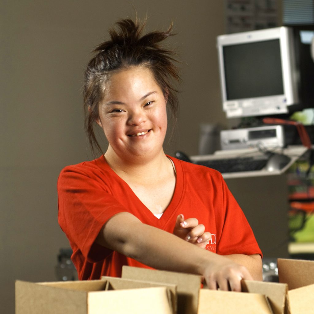 woman with down syndrome in red shirt packing boxes