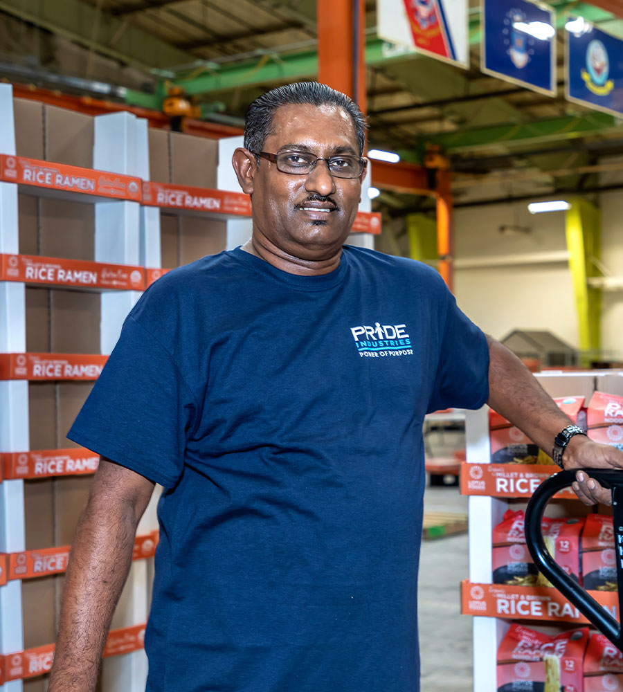 image of man in blue pride industries t shirt and glasses in food packaging warehouse