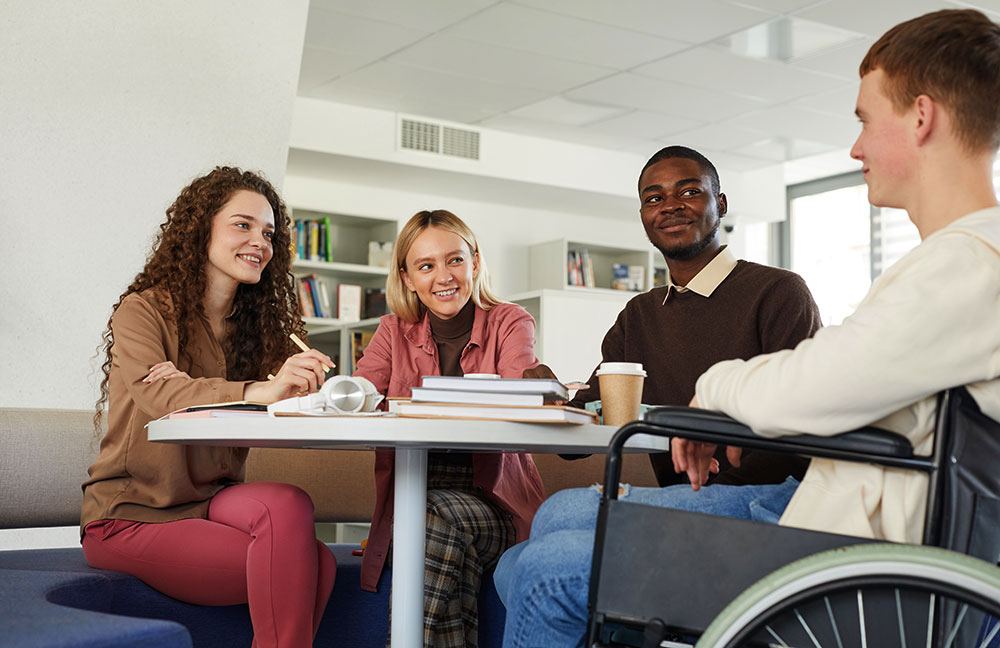 image of four people sitting at table talking one in wheelchair