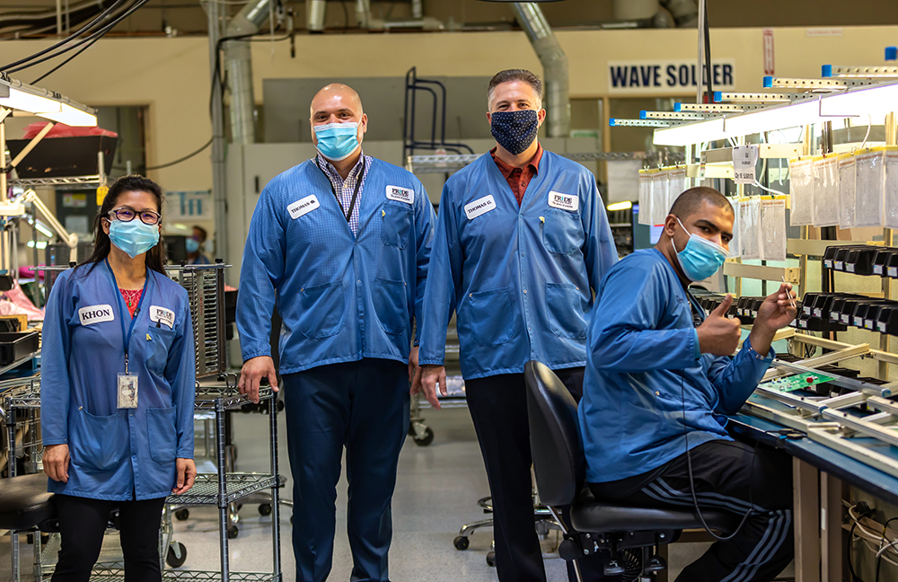 image of four people in PRIDE industries uniforms working in manufacturing floor