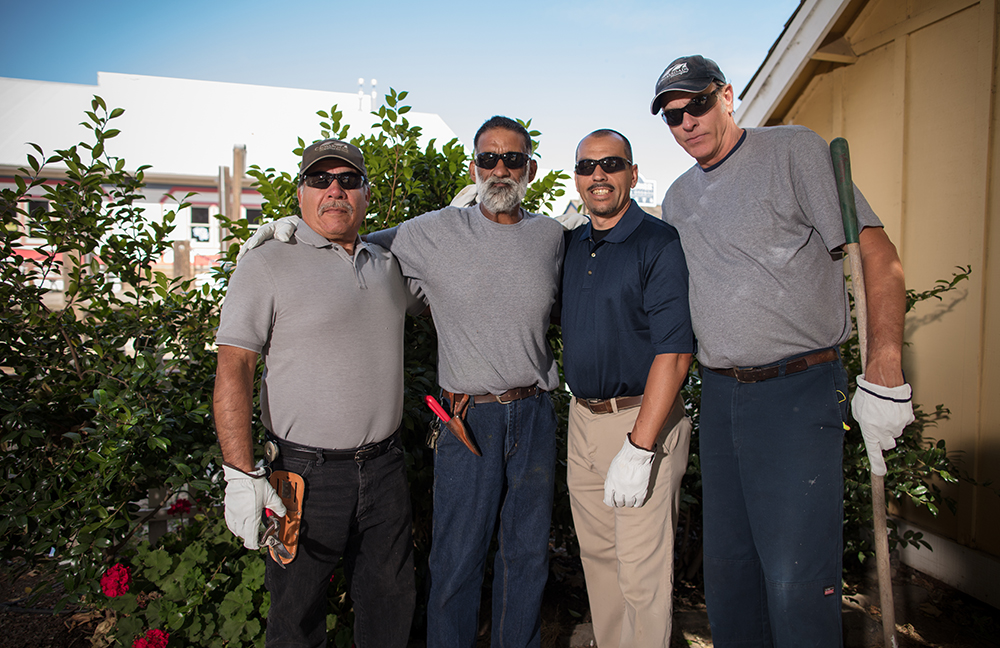 four men in gardening gloves and sunglasses smiling