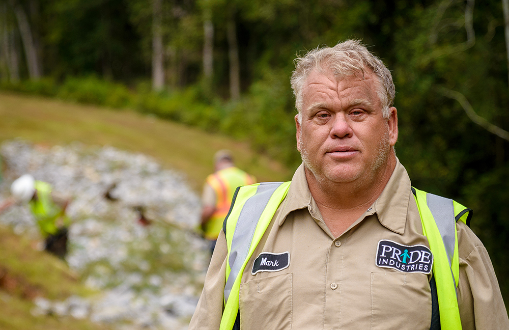 man with down syndrome wearing pride industries uniform and safety vest