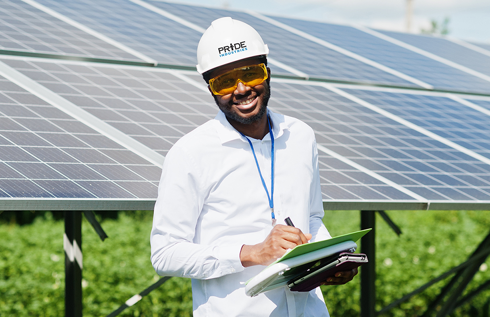 A man in safety glasses and hard hat standing in front of solar panels