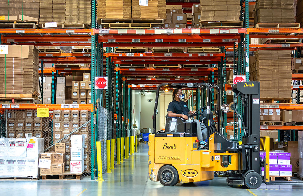 image of man in mask sitting in forklift in warehouse