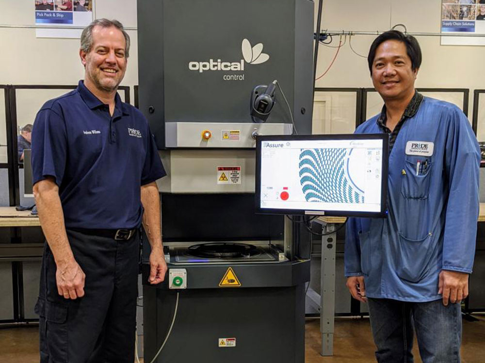 two men standing next to optical control x ray machine