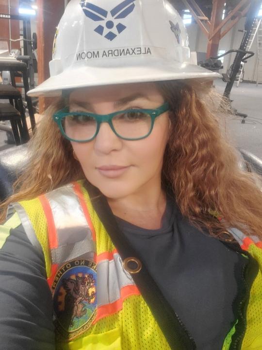 woman wearing hard hat with safety vest on and green glasses