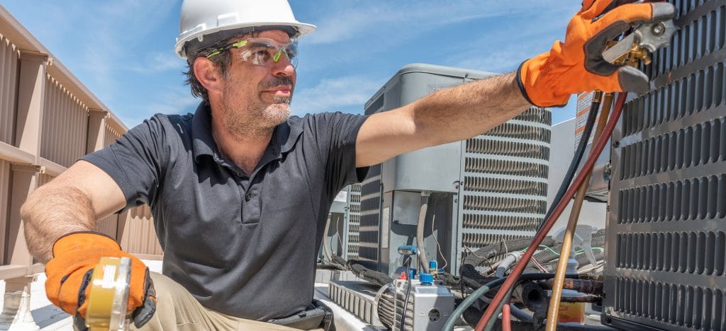 person in white hardhat working on HVAC unit