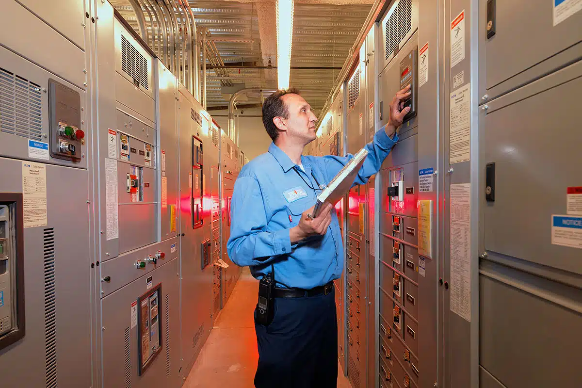 A uniformed technician checks panel readings for a large automated system.