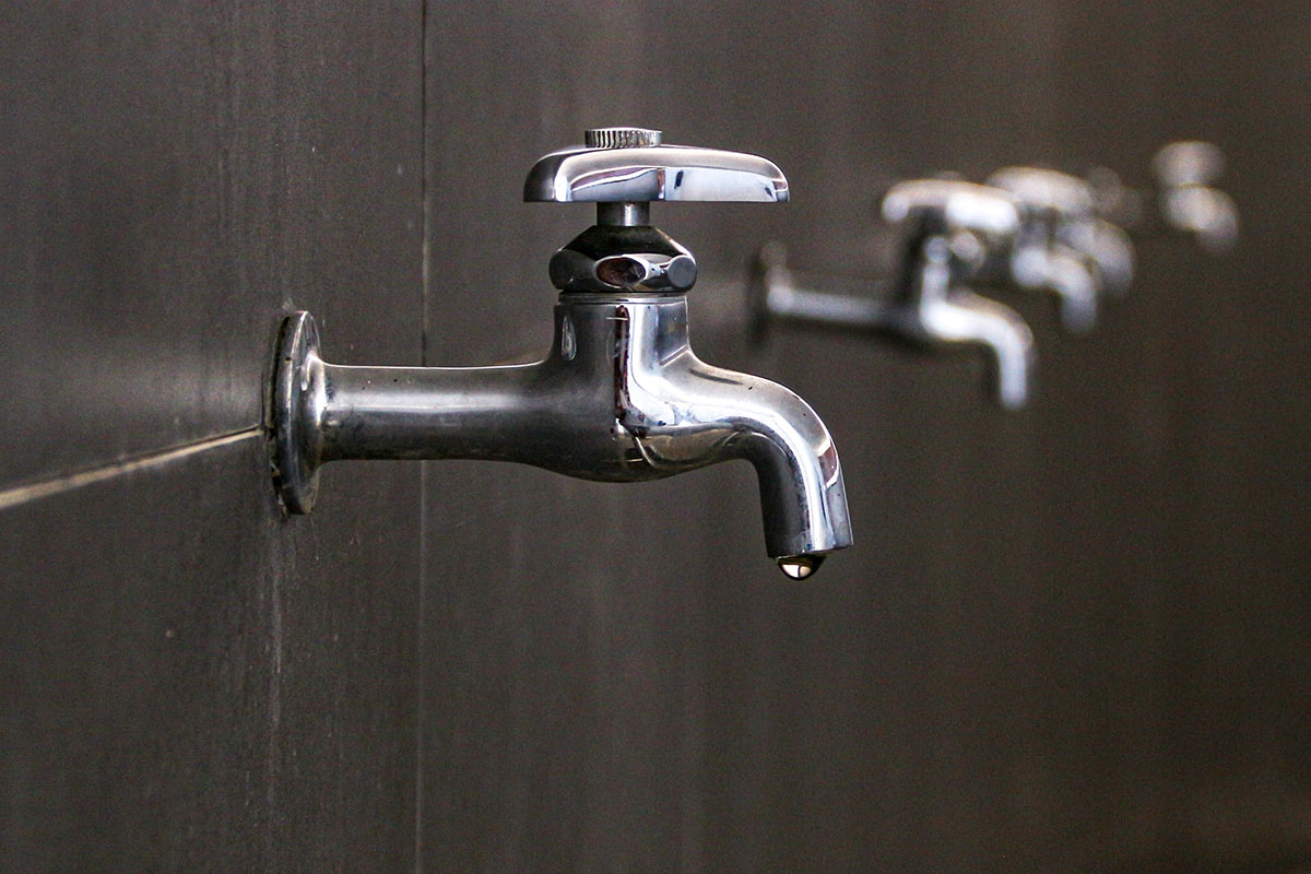 An old-fashioned faucet, with a slow drip, in an office building bathroom